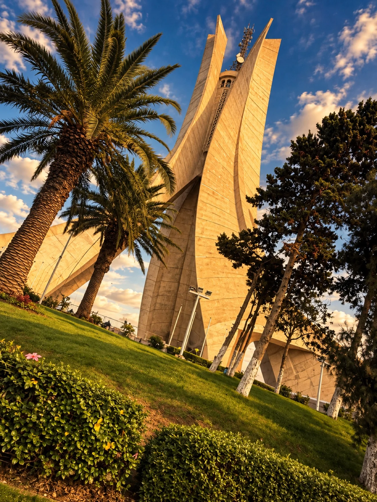 The Martyrs' Memorial in Algiers at golden hour, its three palm-frond pillars rising over the city
